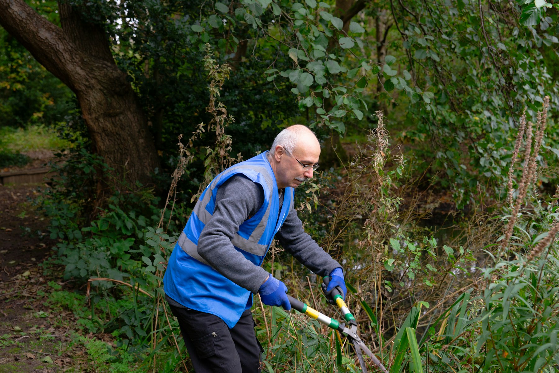 A worker trimming plants outdoors with pruning shears